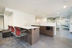 London apartment for rent - resident lounge white countertops and a wooden island with three red chairs