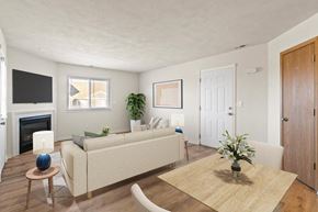 Shiloh apartment for rent - A living room with a beige couch, a fireplace, and a painting on the wall.