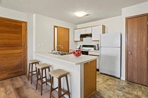 Shiloh apartment for rent - A kitchen with a white refrigerator, wooden bar stools, and a white countertop.