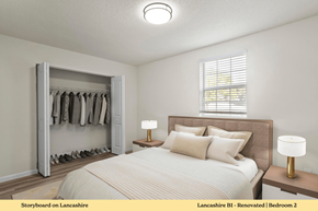 Edwardsville apartment for rent - A bedroom with a large bed, a wooden nightstand with a lamp, and a closet with clothes hanging.