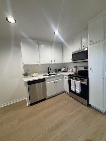 Torrance apartment for rent - A kitchen with white cabinets and a wooden floor.