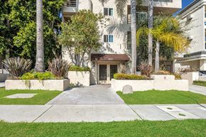 Los Angeles apartment for rent - Image of 9025 Alcott Apartment building with a brown awning is surrounded by greenery.