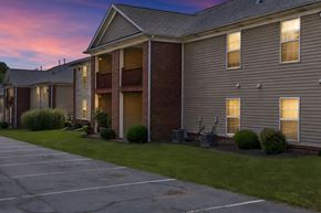 Shelbyville apartment for rent - A parking lot in front of a building with a sunset in the background.