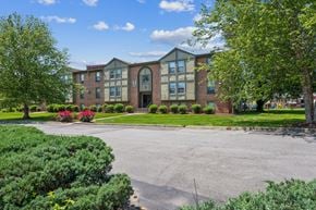Louisville apartment for rent - A large building with a red brick facade and a green lawn in front.