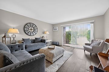 Carol Stream apartment for rent - A living room with grey couches and a large clock on the wall.
