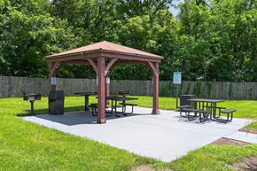 Shelbyville apartment for rent - A gazebo with picnic tables is surrounded by a fence and trees.