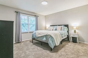 Spartanburg apartment for rent - A bedroom with a bed, nightstand, and window.
