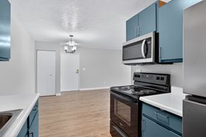 Battle Creek apartment for rent - A kitchen with blue cabinets and a stove top oven.