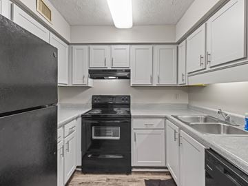 Montgomery apartment for rent - A black refrigerator is on the left in a kitchen with white cabinets.
