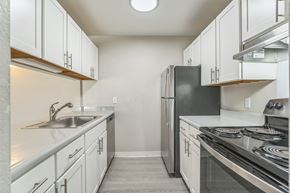 Holland apartment for rent - A kitchen with white cabinets and a black refrigerator.