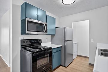 Battle Creek apartment for rent - A kitchen with a black stove and blue cabinets.