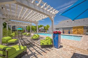 Fenton apartment for rent - A poolside area with green lounge chairs and a white pergola.
