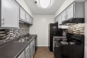 Evansville apartment for rent - A kitchen with black appliances and a stone backsplash.