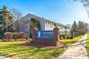 Port Huron apartment for rent - The image shows the entrance to Lighthouse Estates with a sign and a building in the background.
