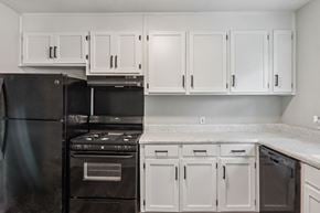 Spartanburg apartment for rent - A black refrigerator and oven in a kitchen with white cabinets.