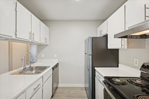 Parchment apartment for rent - A kitchen with white cabinets and a black stove top oven.