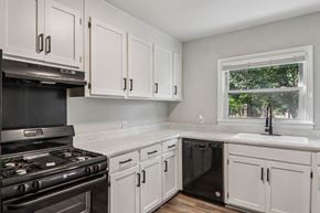 Spartanburg apartment for rent - A kitchen with white cabinets and a black stove top oven.