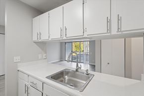 Parchment apartment for rent - A kitchen with white cabinets and a stainless steel sink.