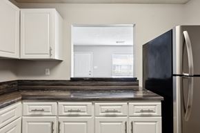 Prattville apartment for rent - A kitchen with white cabinets and a black refrigerator.