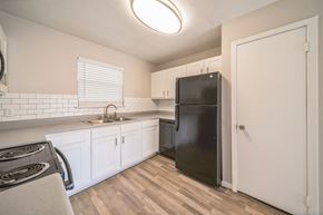 Auburn apartment for rent - A black refrigerator in a kitchen with white cabinets.