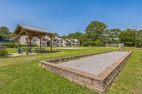 Mobile apartment for rent - A playground with a sandbox and picnic tables in a grassy area.