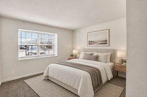 Evansville apartment for rent - A bedroom with a large bed and a window overlooking a cityscape.
