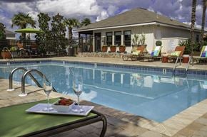 Prattville apartment for rent - A poolside table with a plate of food and two glasses of wine.