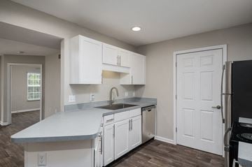 Louisville apartment for rent - a kitchen with white cabinets and a sink and a refrigerator
