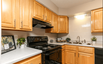 Louisville apartment for rent - A kitchen with wooden cabinets and black appliances.