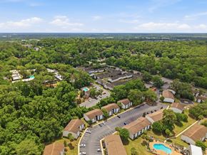 Tallahassee apartment for rent - A bird's eye view of a residential area with houses, a swimming pool, and a parking lot.