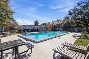 Tallahassee apartment for rent - A pool surrounded by trees and a sunny sky.