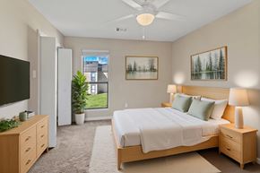 Lake Charles apartment for rent - A bedroom with a large bed, a television, and a potted plant.