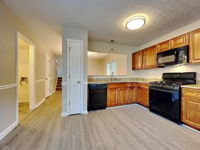 Hampton house for rent - an empty kitchen with wooden cabinets and black appliances