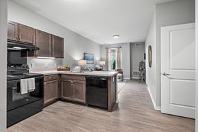 Columbus apartment for rent - a kitchen with wooden cabinets and black appliances and a hallway to a living room