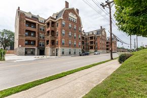 Cincinnati apartment for rent - A large red brick building with a green lawn in front.