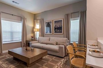 Union City apartment for rent - A living room with a grey couch, a coffee table, and a dining table set for two.