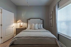 Union City apartment for rent - A bedroom with a large bed and a nightstand with a lamp.