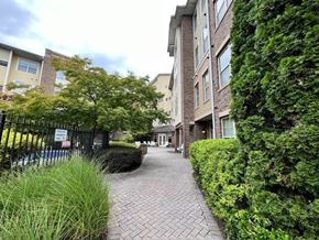 Atlanta apartment for rent - A brick pathway leads through a green hedge to a building.