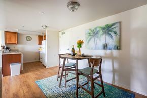 New Port Richey apartment for rent - A dining room with a table and chairs and a painting of a palm tree on the wall.