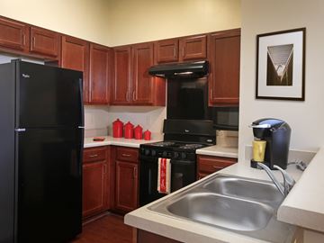 Lithonia apartment for rent - A black refrigerator sits in a kitchen with brown cabinets.