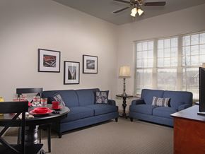 Lithonia apartment for rent - A living room with a blue couch, a black table, and a ceiling fan.