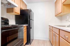 Montgomery apartment for rent - A kitchen with a black refrigerator and wooden cabinets.