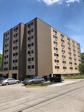 Montgomery apartment for rent - A large tan building with many windows sits next to a parking lot.