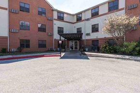 San Antonio apartment for rent - A building with a red and white exterior and a tree in front.
