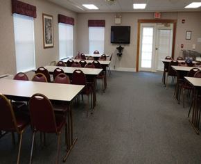 Wilkinsburg apartment for rent - A room with tables and chairs and a TV on the wall.