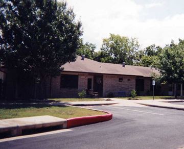 Austin apartment for rent - A building with a brown roof and a tree in front of it.