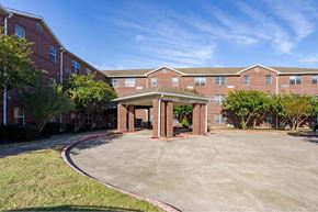 Houston apartment for rent - A parking lot in front of a brick building with a covered walkway.