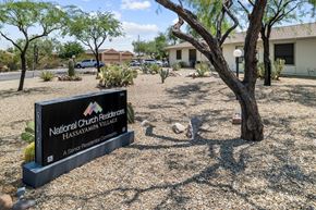 Wickenburg apartment for rent - A sign for National Church Residences Hassayampa Village stands in front of a tree.