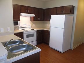 Atlanta apartment for rent - A white refrigerator stands in a kitchen with brown cabinets.