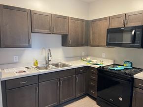 Atlanta apartment for rent - A kitchen with brown cabinets and a black stove top oven.